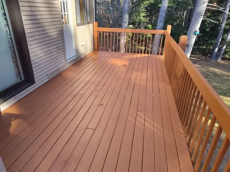 Wooden deck with reddish-brown stain and railing attached to house